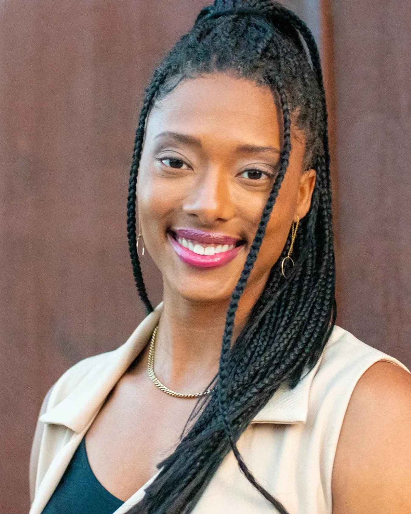 Portrait of Blake Bolden smiling, long braids over one shoulder