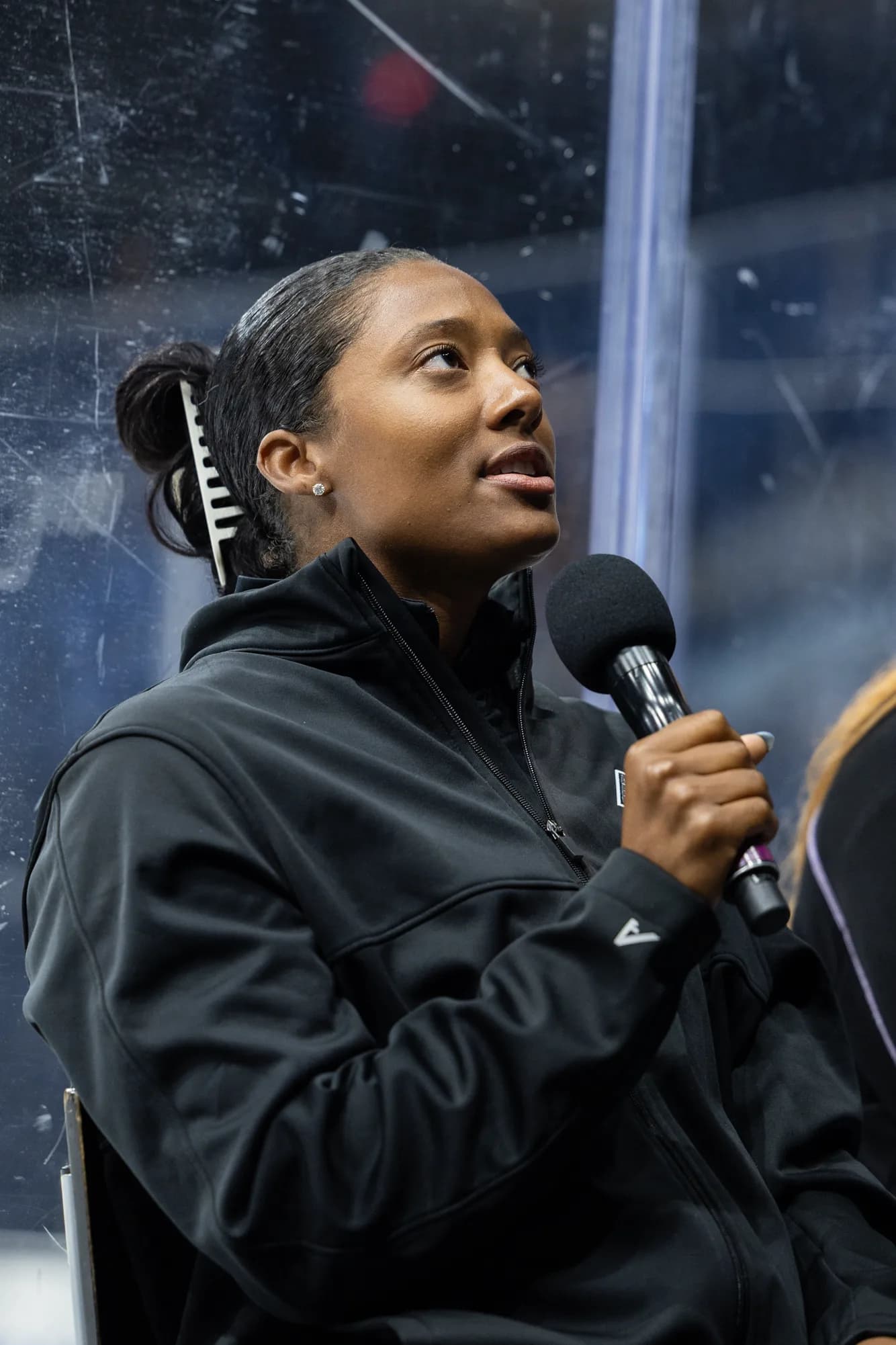 Blake Bolden seated by the glass at a rink, speaking into a microphone