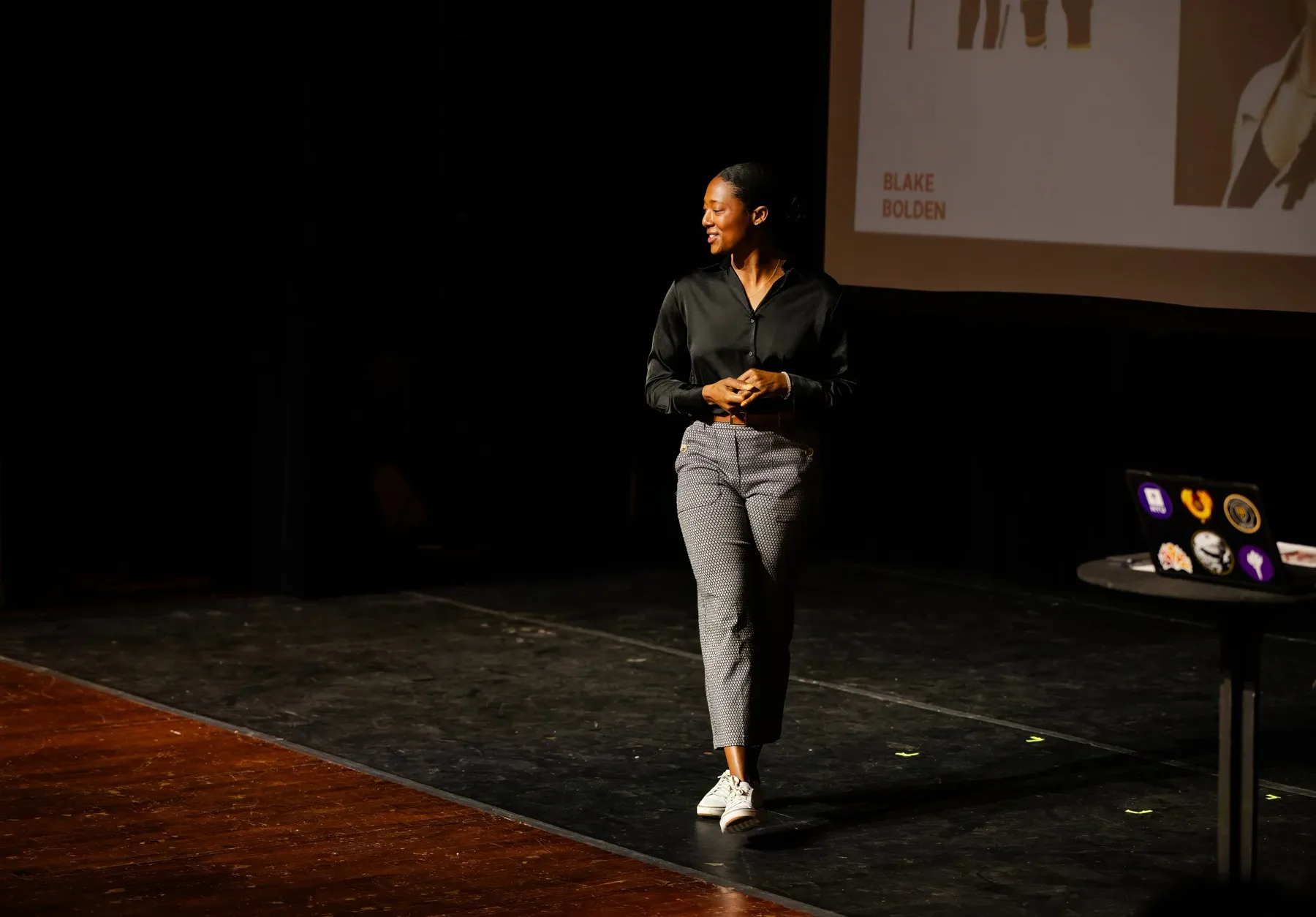 Blake Bolden walking across a dark stage during a talk